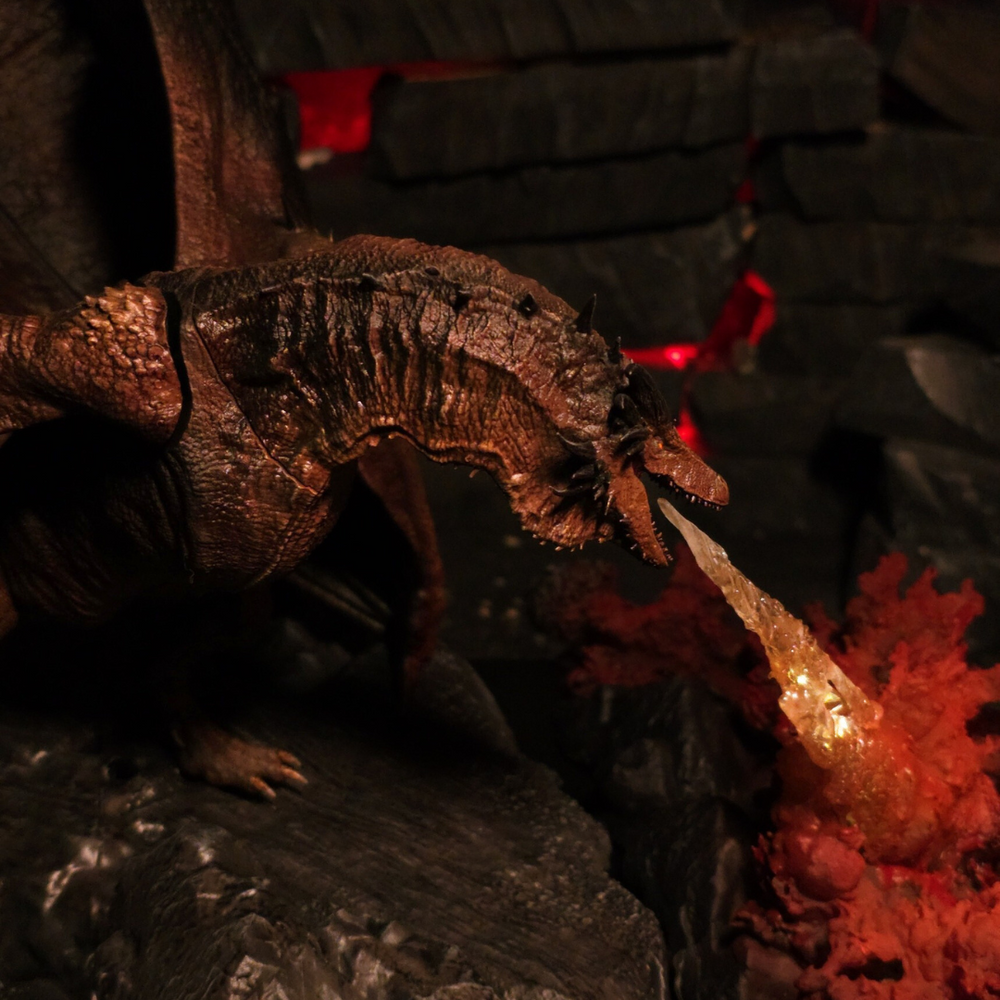 
                  
                    Vue latérale du dragon Bronze Fury crachant du feu, avec ses ailes déployées et son cou recourbé, en pleine action.
                  
                